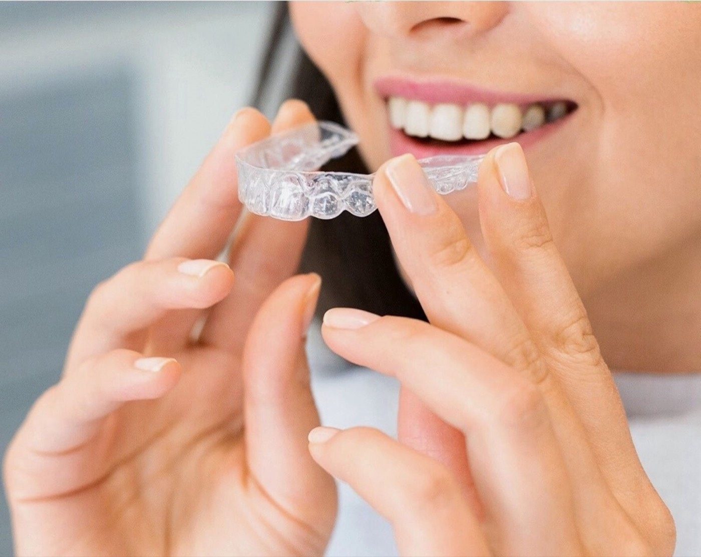 A clear orthodontic aligner held up to the light